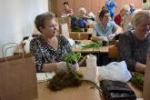 Seniorki obwijają mchem korzenie roślin wraz z ziemią tworząc kokedamę.